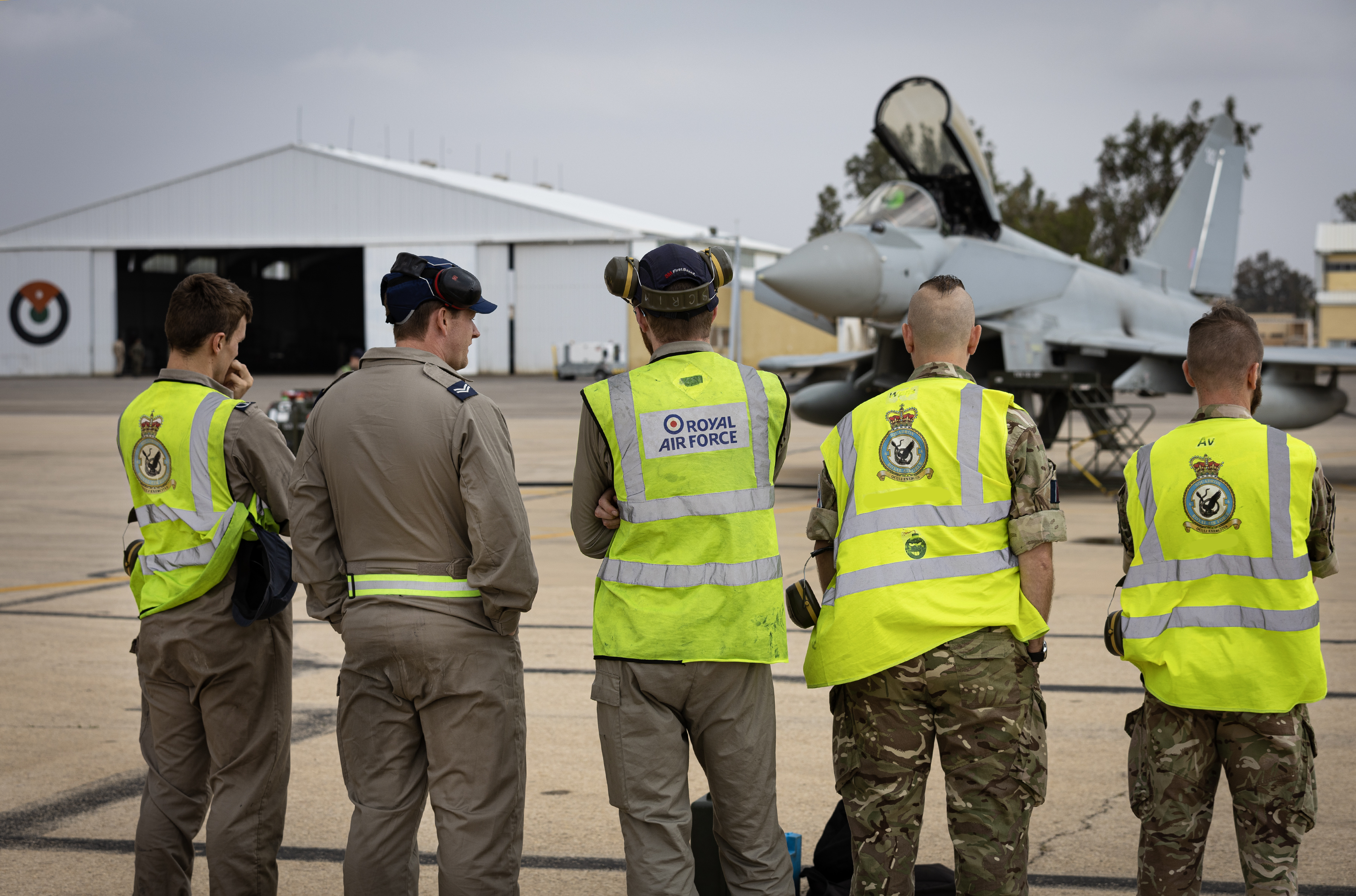 Image shows RAF aviators standing in a line looking towards a RAF Typhoon on the airfield.
